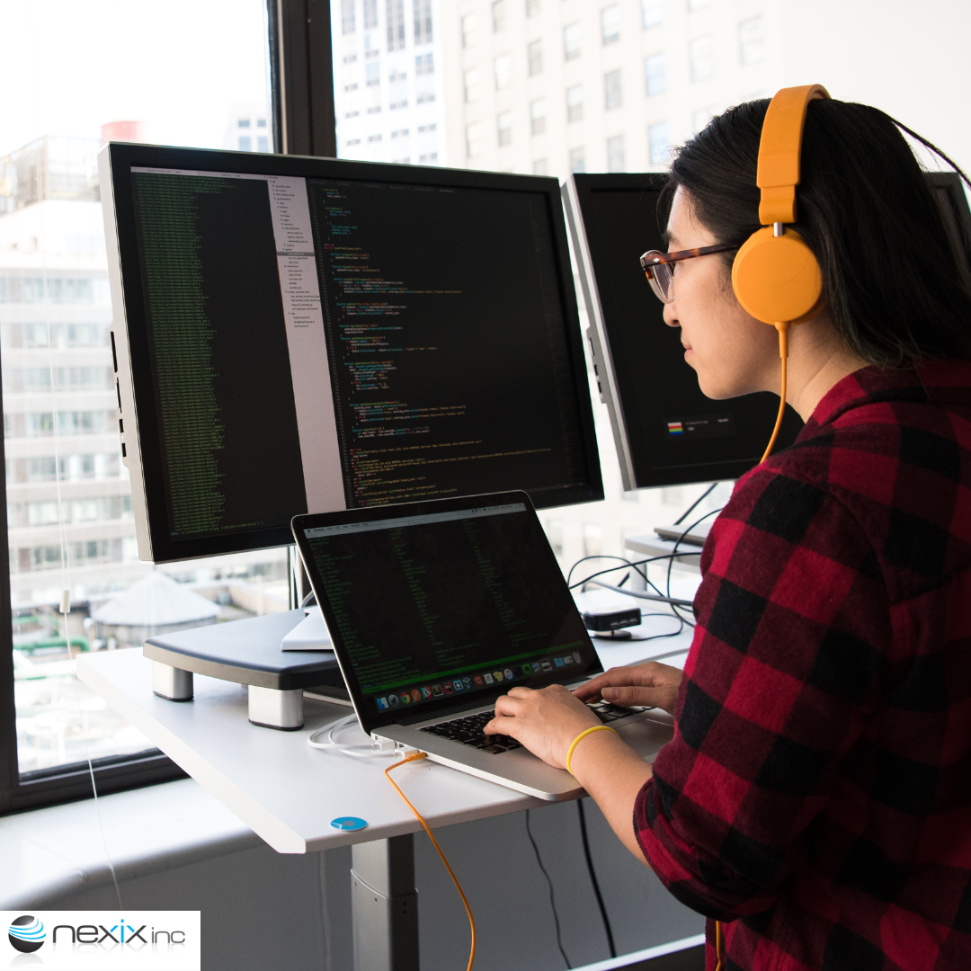 Woman coding on 3 screens at a desk