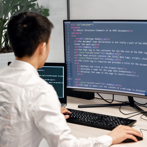 Man coding on 2 screens at a desk