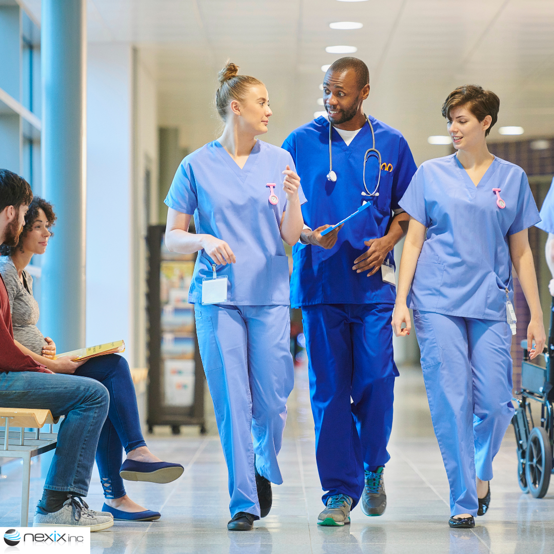 Three hospital workers walking down a hallway with 2 patients on the left side