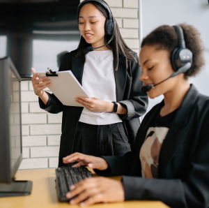 two working women on computers with headsets