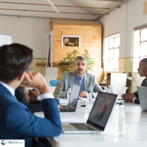 Team of three men talking in a conference room with laptops