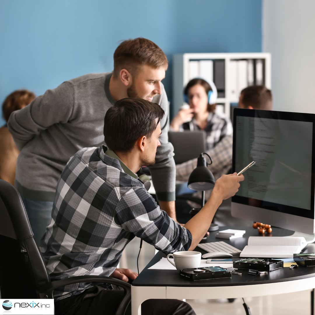 2 men working at a desk looking at a computer