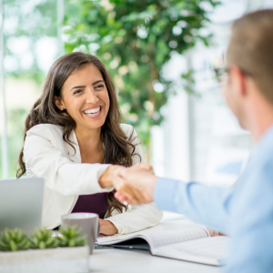 2 people shaking hands over a desk